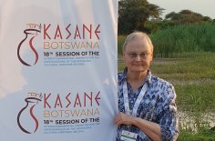 Kristin Kuutma in Botswana with the logo of the event and a landscape in the background